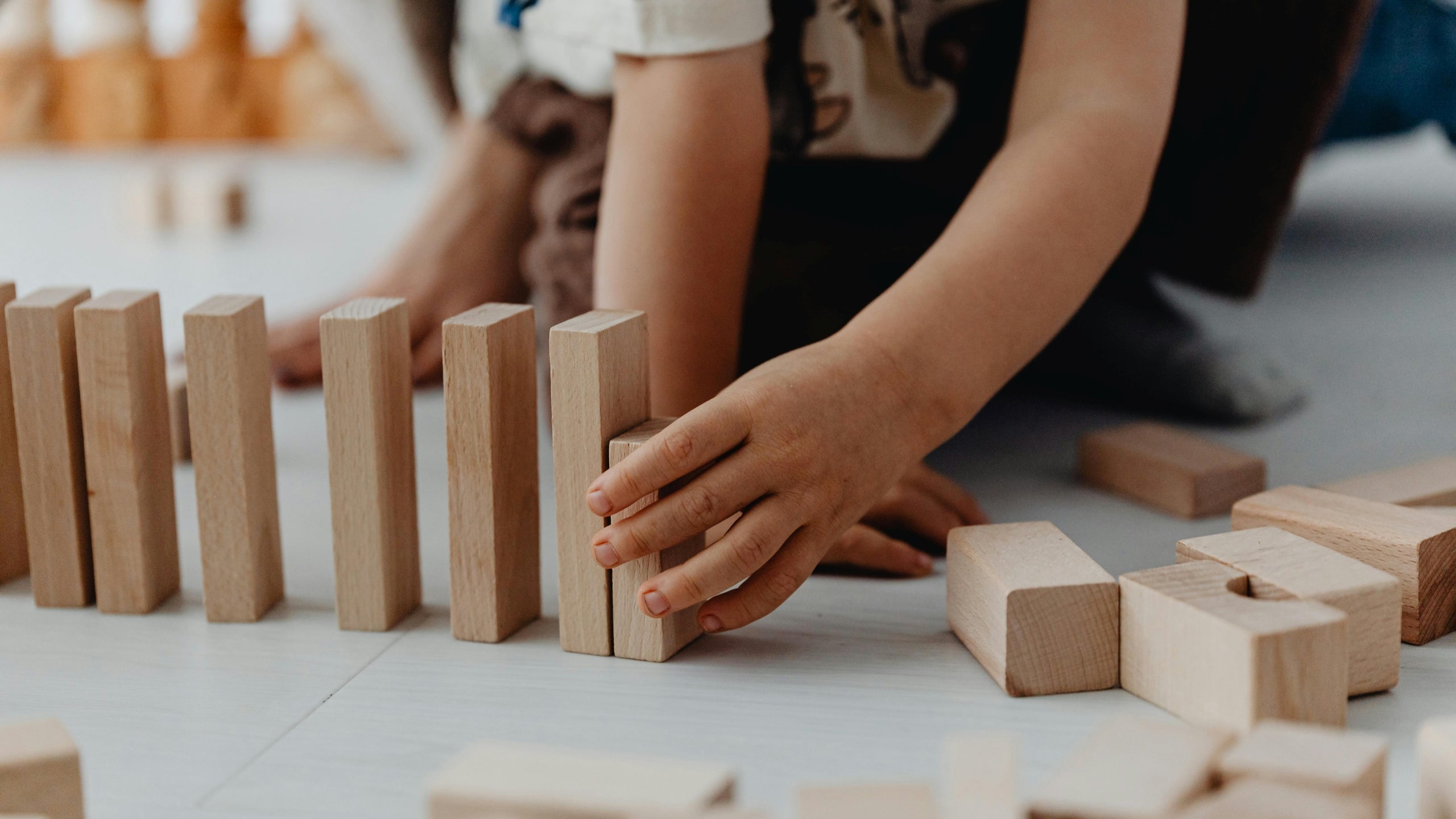 Toddler playing with wooden blocks on a light-colored floor.